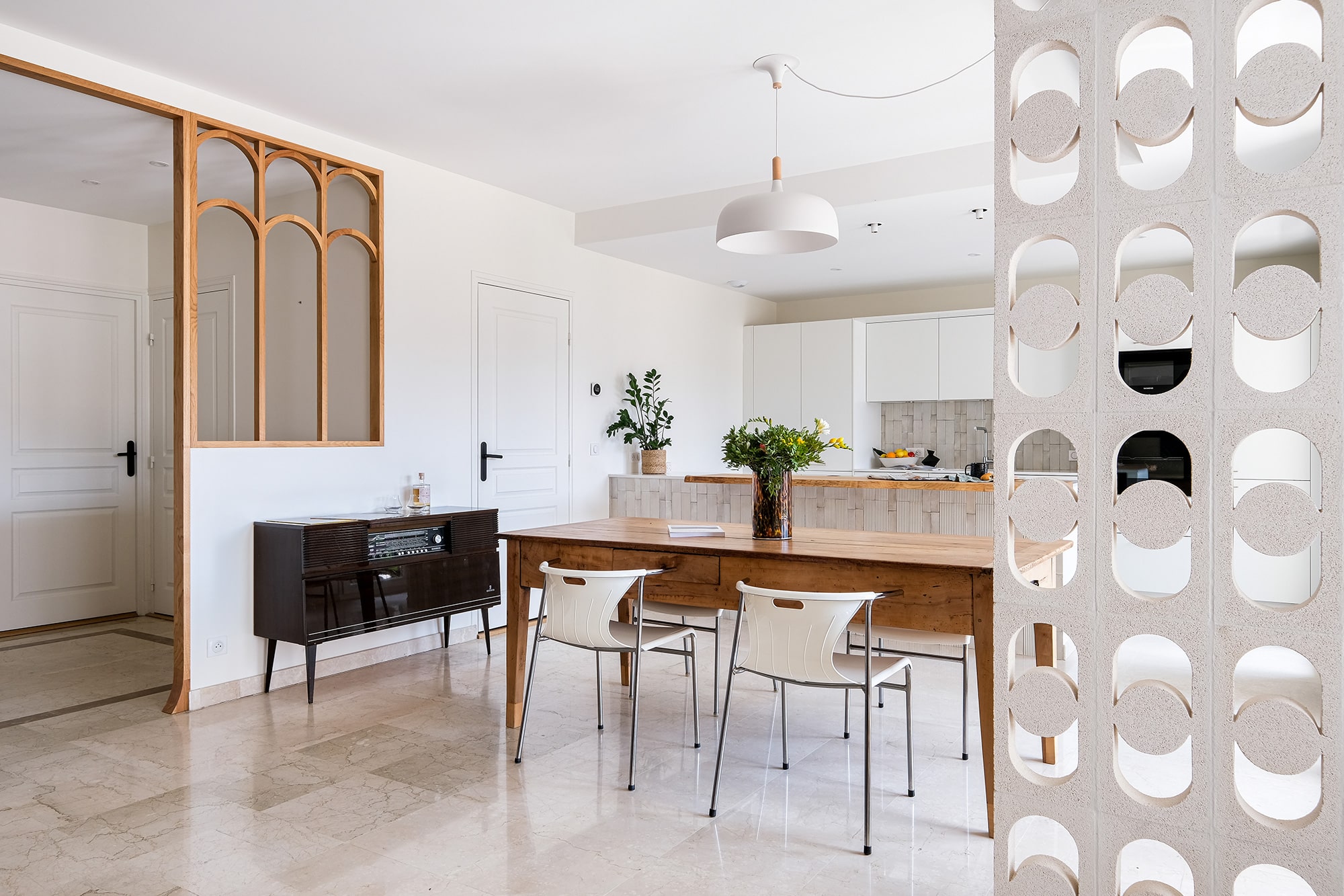 Celosía blanca separando una cocina de un comedor, permitiendo el paso de la luz.